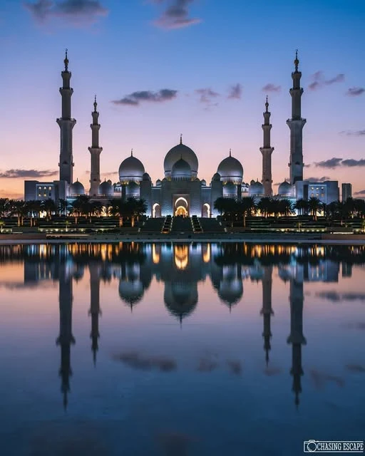 Grand illuminated architecture reflected in water at blue hour